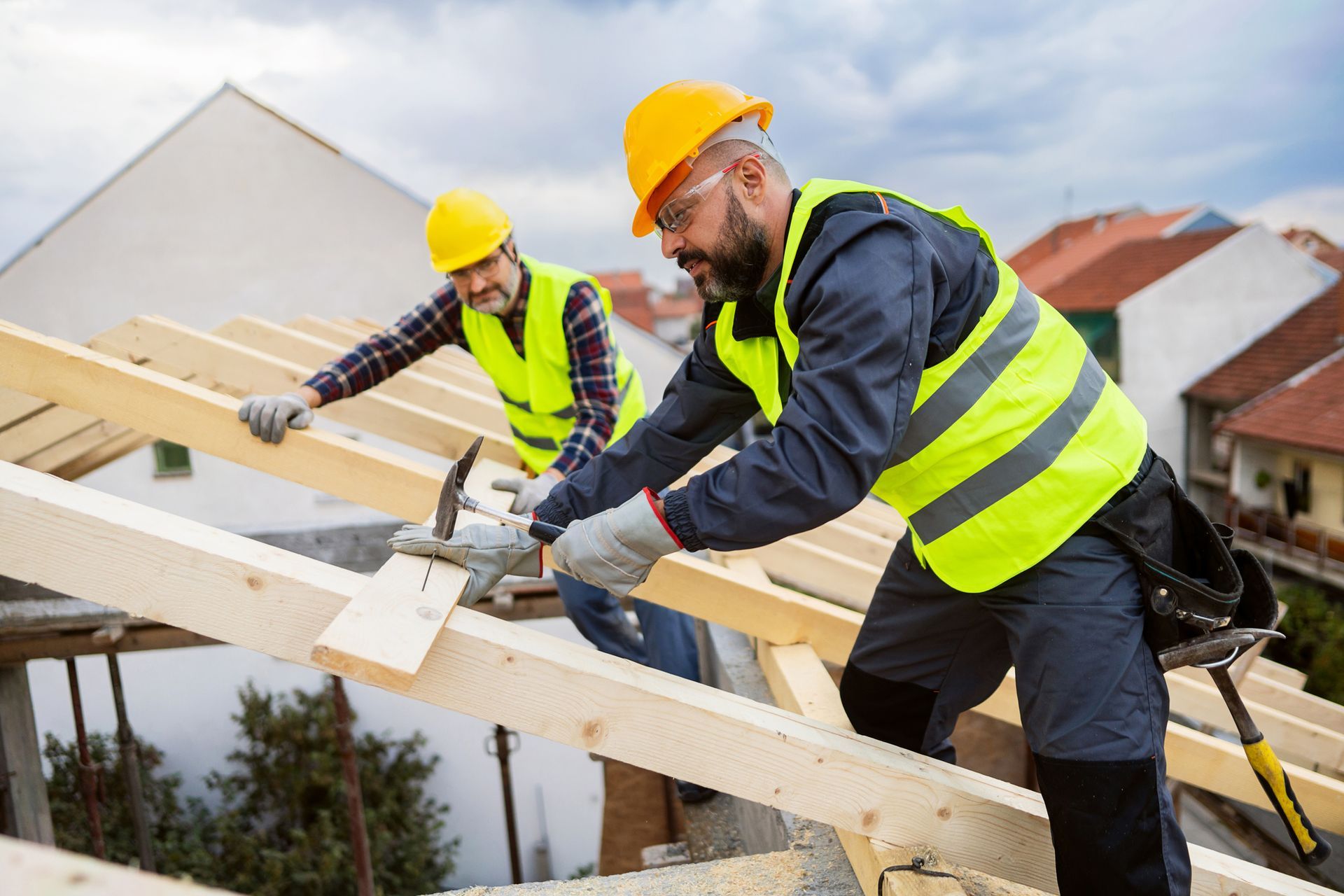 Two male roofers, using nails and hammer while making a roof beam.