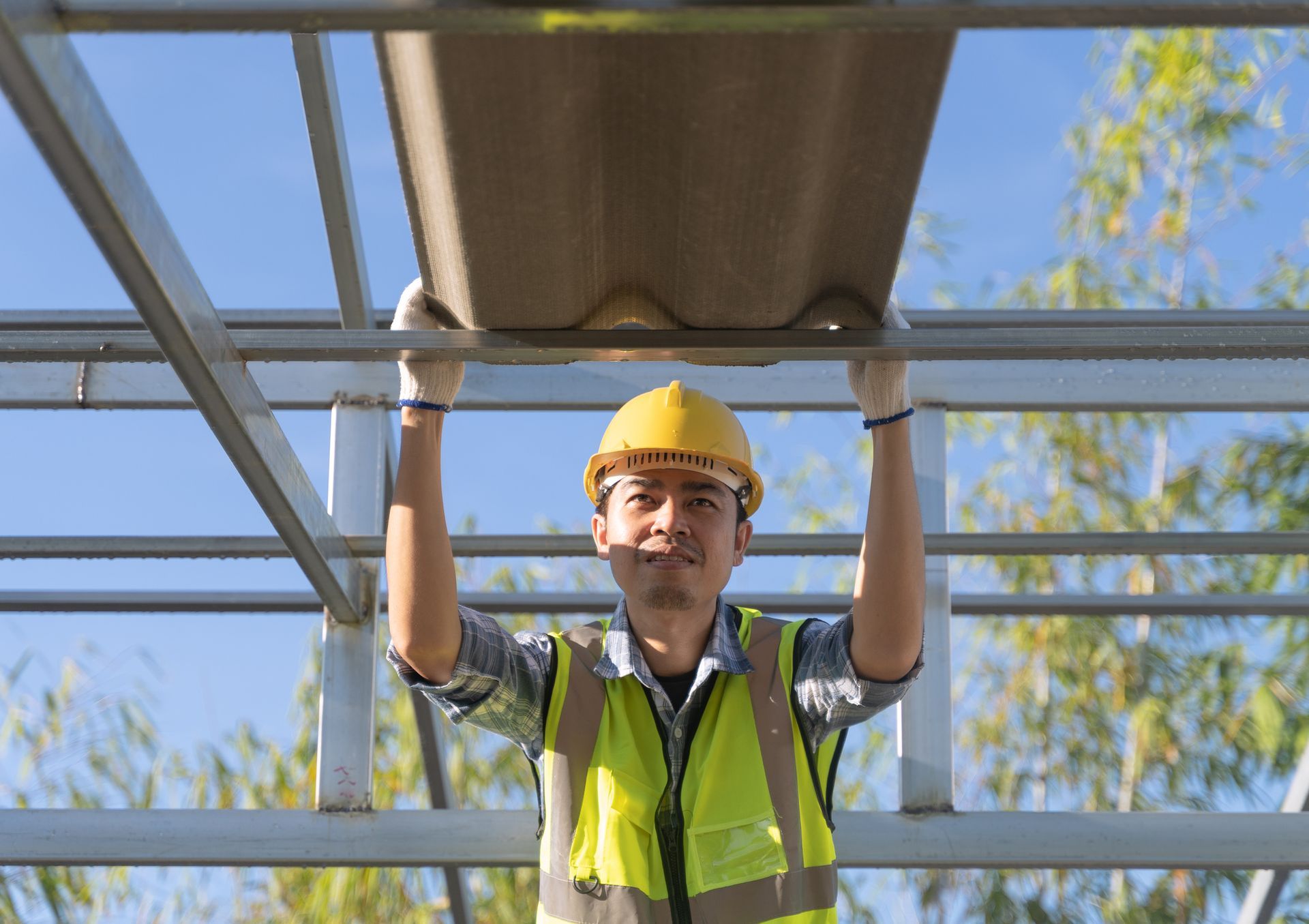 Construction worker installing roof tiles at roof of house.