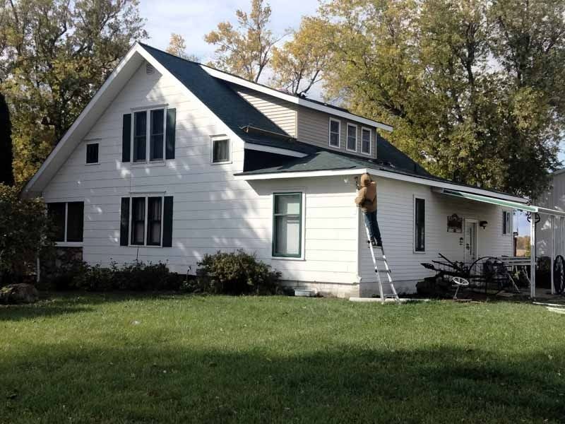 A man standing on a ladder in front of a white house
