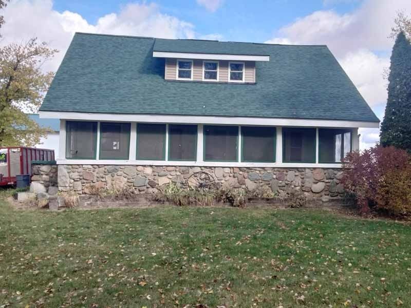 A house with a screened in porch and a green roof