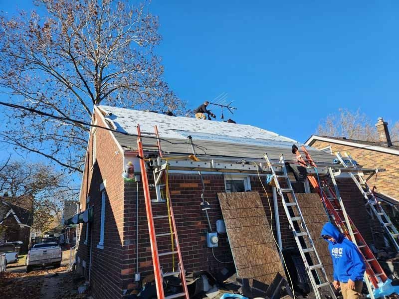 A group of people are working on the roof of a brick house.