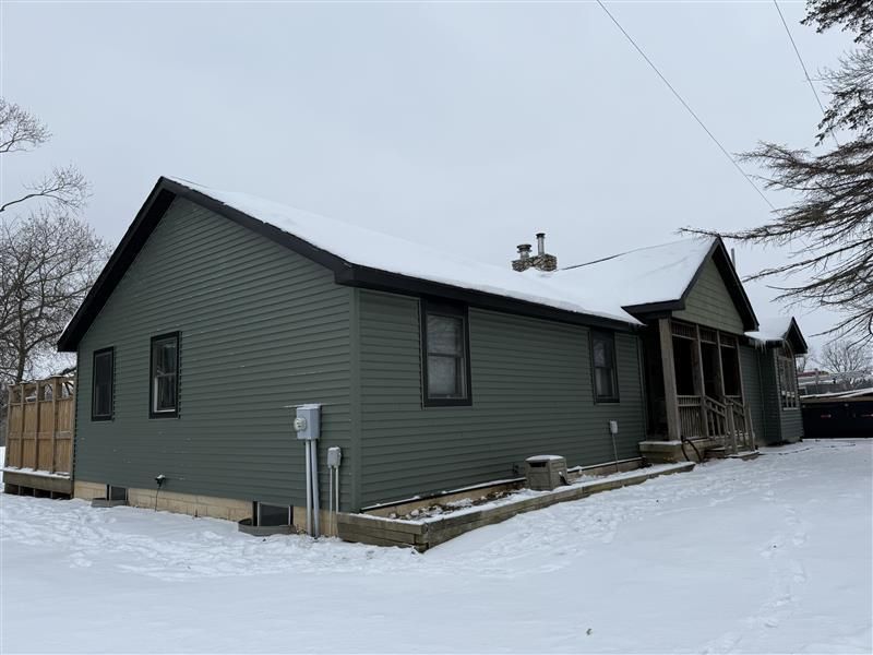 The front door of a house with a black door and a stone wall.