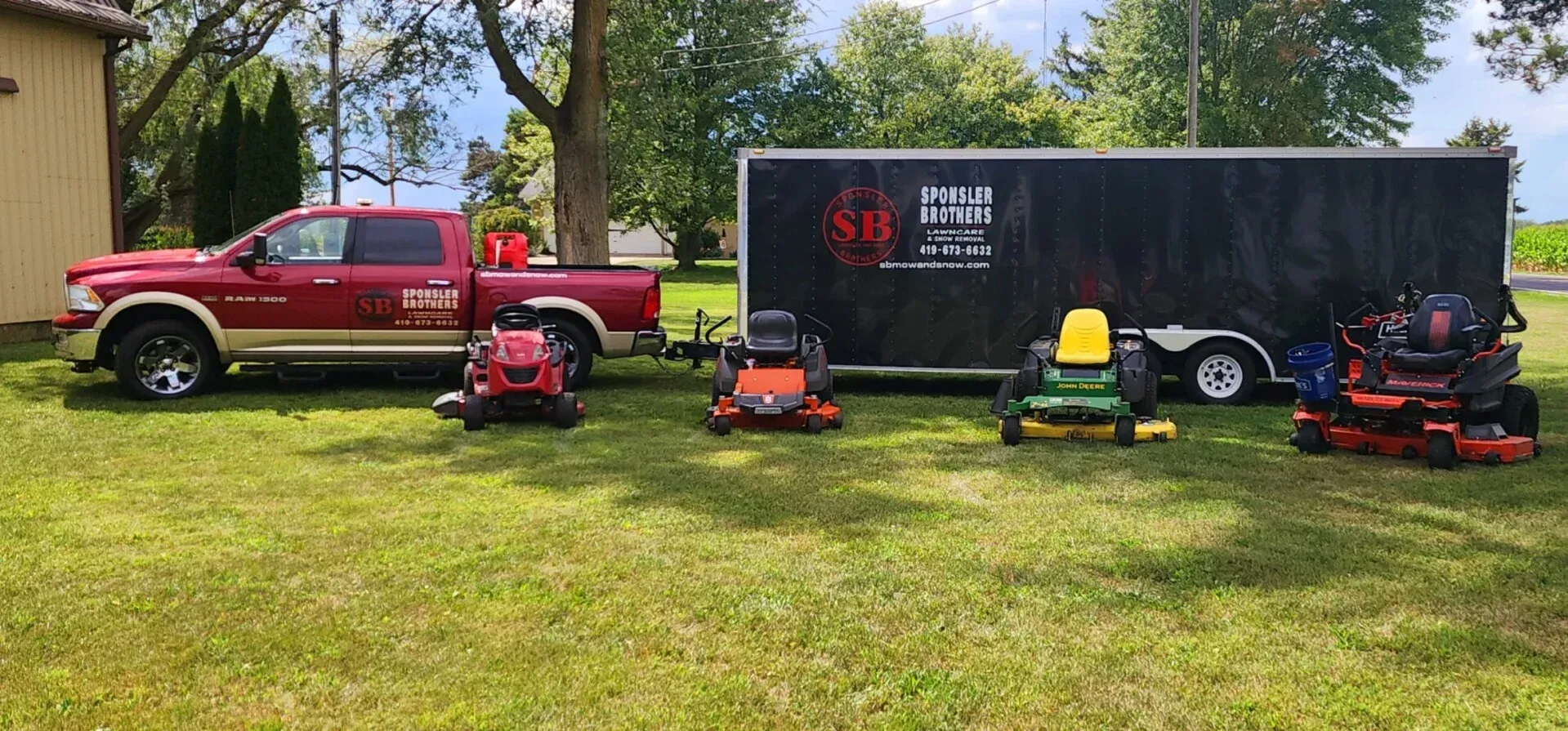 Red pickup truck, mower, and trailer with lawn equipment on grass in a sunny yard