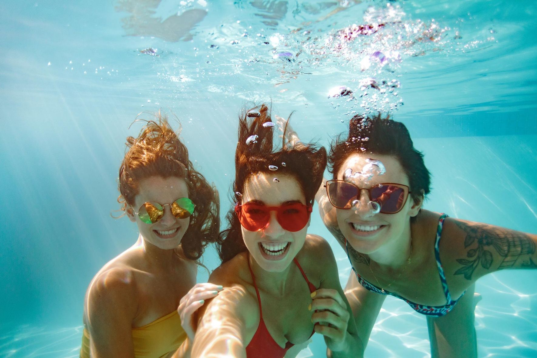 Happy friends underwater in a pool