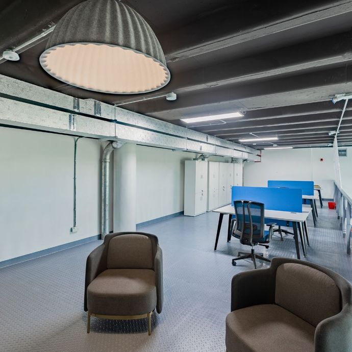 Two women in armchairs in an office, discussing with a laptop and documents. Modern, open-plan office setting.