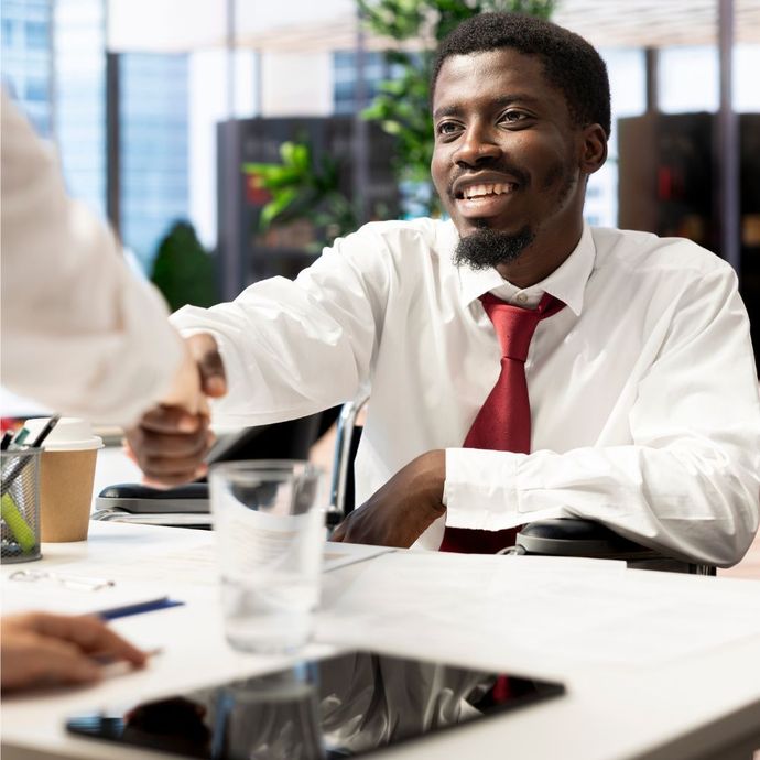 Two women in armchairs having a discussion in a modern office with large windows.