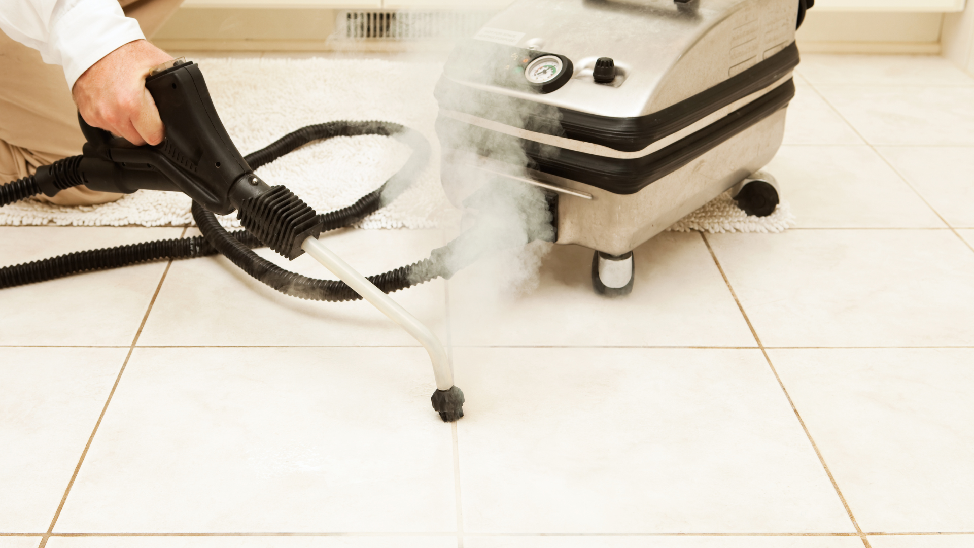 A person is using a steam cleaner to clean a tile floor.
