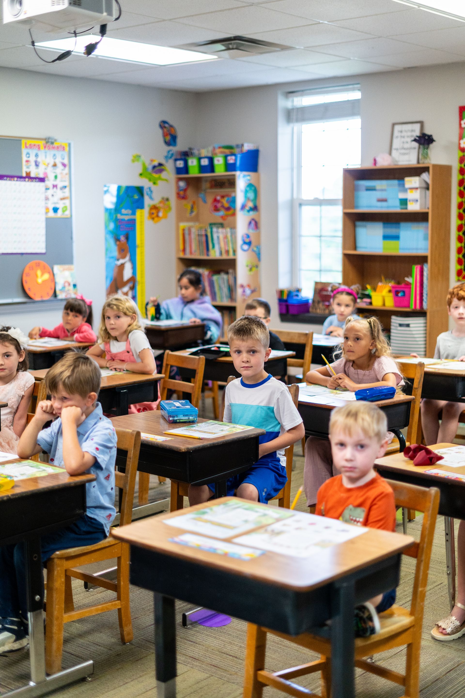 Lawn area with cornhole boards, strung lights, white walls, and a building in the background.