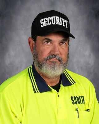 Man wearing a security cap and fluorescent shirt, looking directly at the viewer.