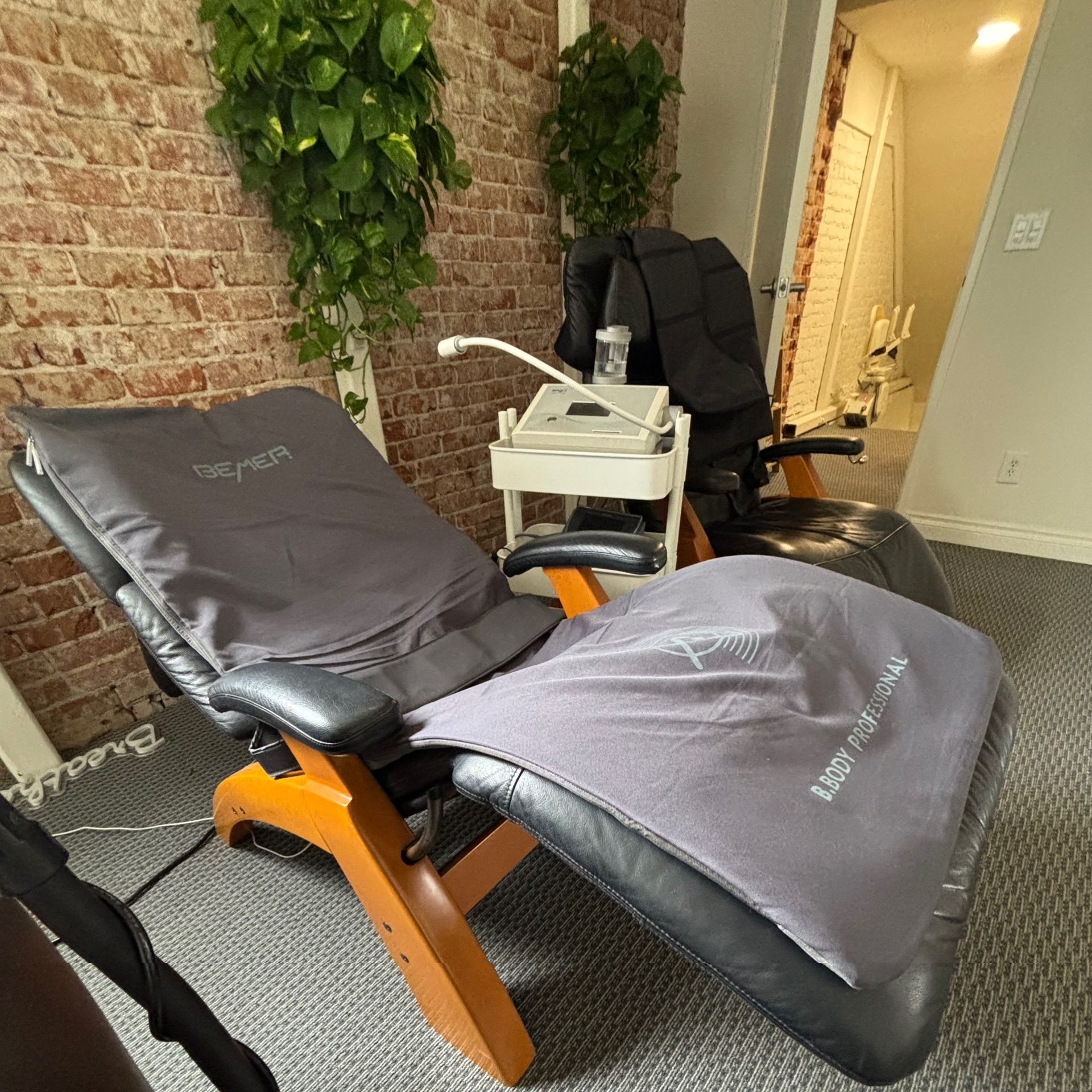 A woman is drinking water from a bottle in front of a window.