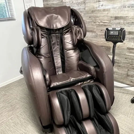 A brown massage chair is sitting in a room next to a wooden wall.