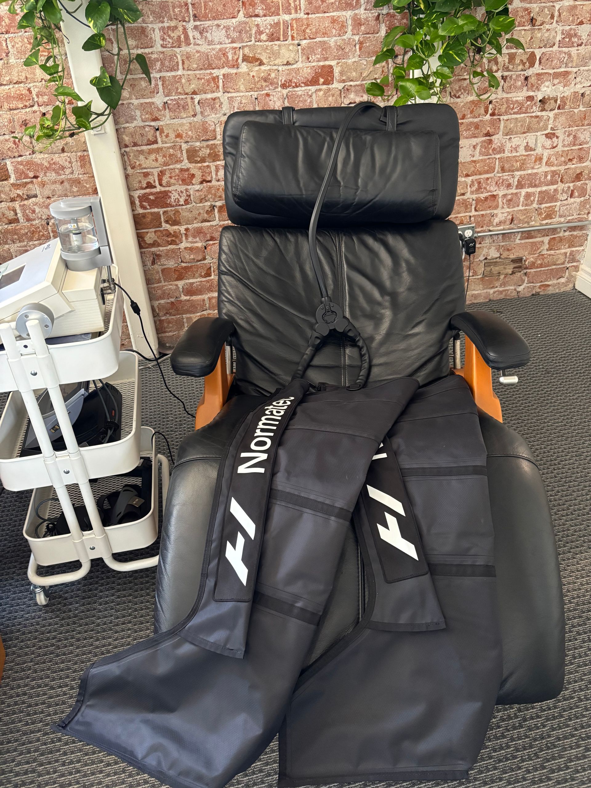A black chair with a bag on it is sitting in front of a brick wall.