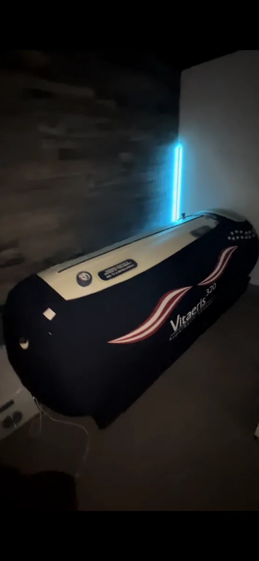 A bed with a blue light coming out of it in a dark room.