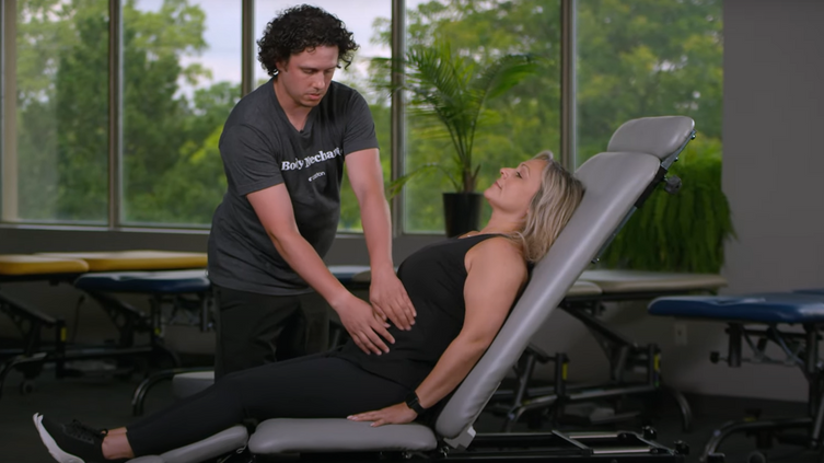 A man is giving a woman a massage while she is laying on a table.