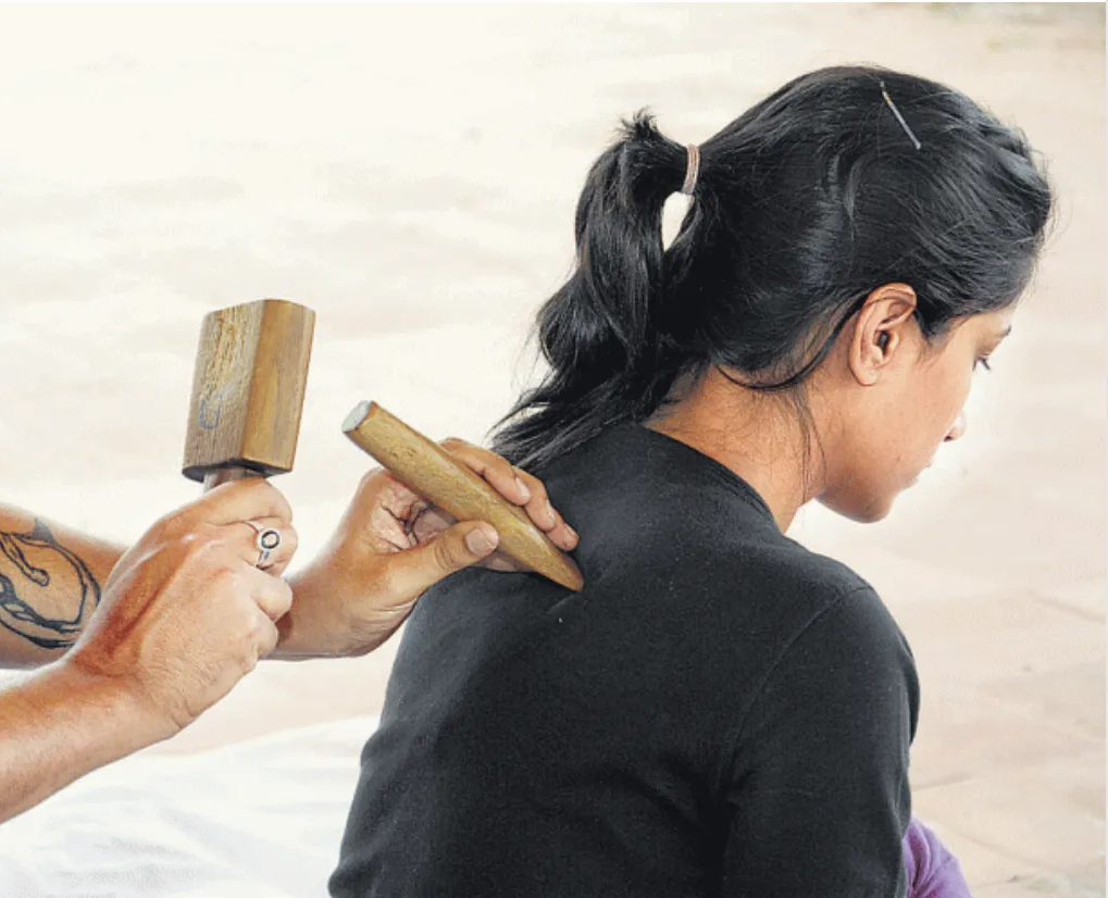 A woman is getting a massage with a wooden stick