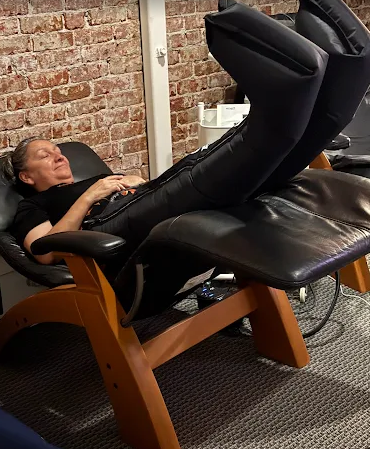 A woman is laying in a chair with her legs up.