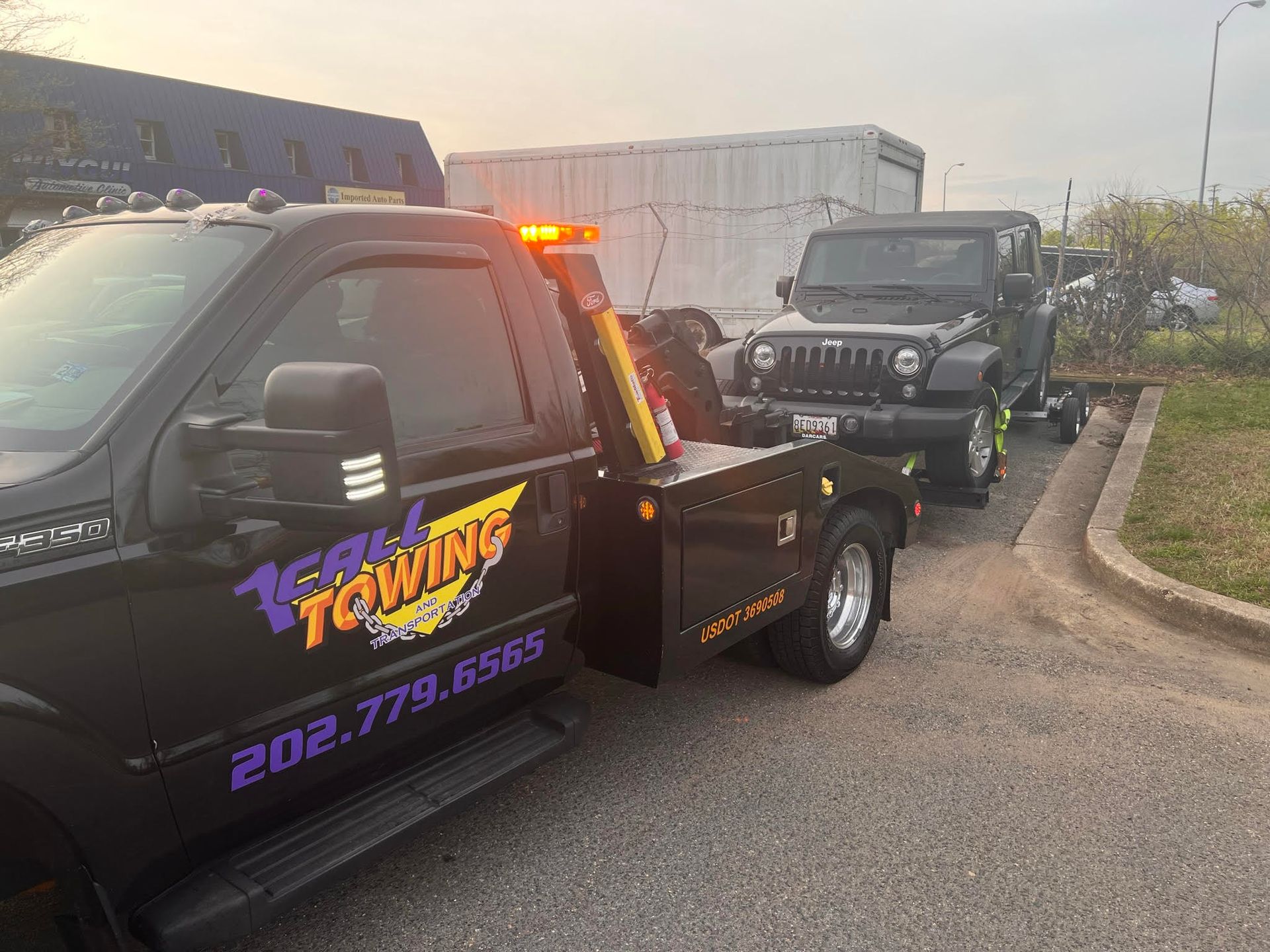 A tow truck is towing a jeep in a parking lot.