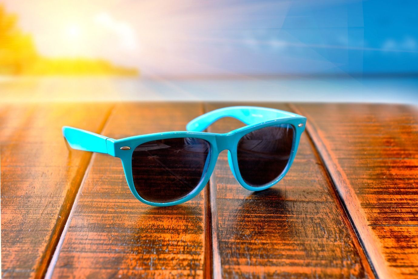 Un par de gafas de sol azules están sobre una mesa de madera.