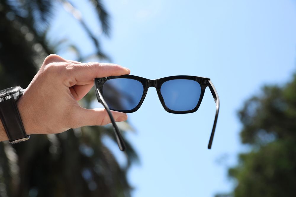 Una persona sostiene un par de gafas de sol en su mano.