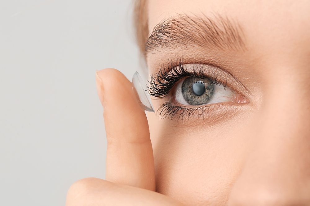 Una mujer se pone una lente de contacto en el ojo.