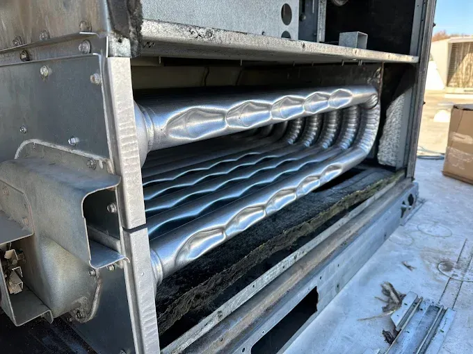 Open view of a metallic heat exchanger with corrugated tubes inside a rectangular frame.