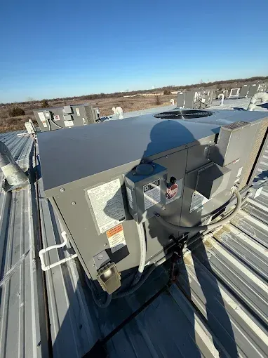 Large rooftop HVAC unit on a metal roof, under a bright blue sky.