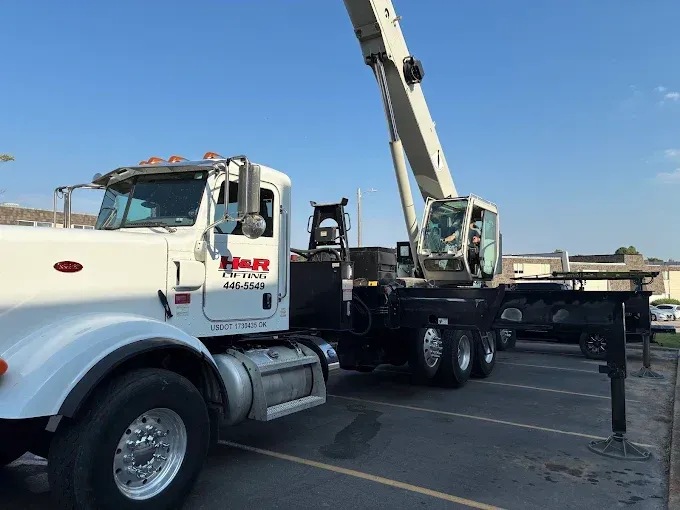 White crane truck in a parking lot with its arm extended.