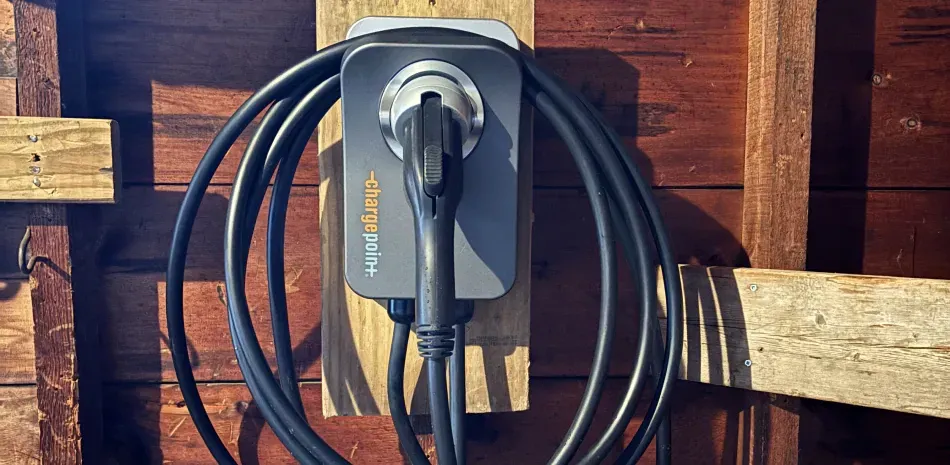 An electric car charger is hanging on a wooden wall