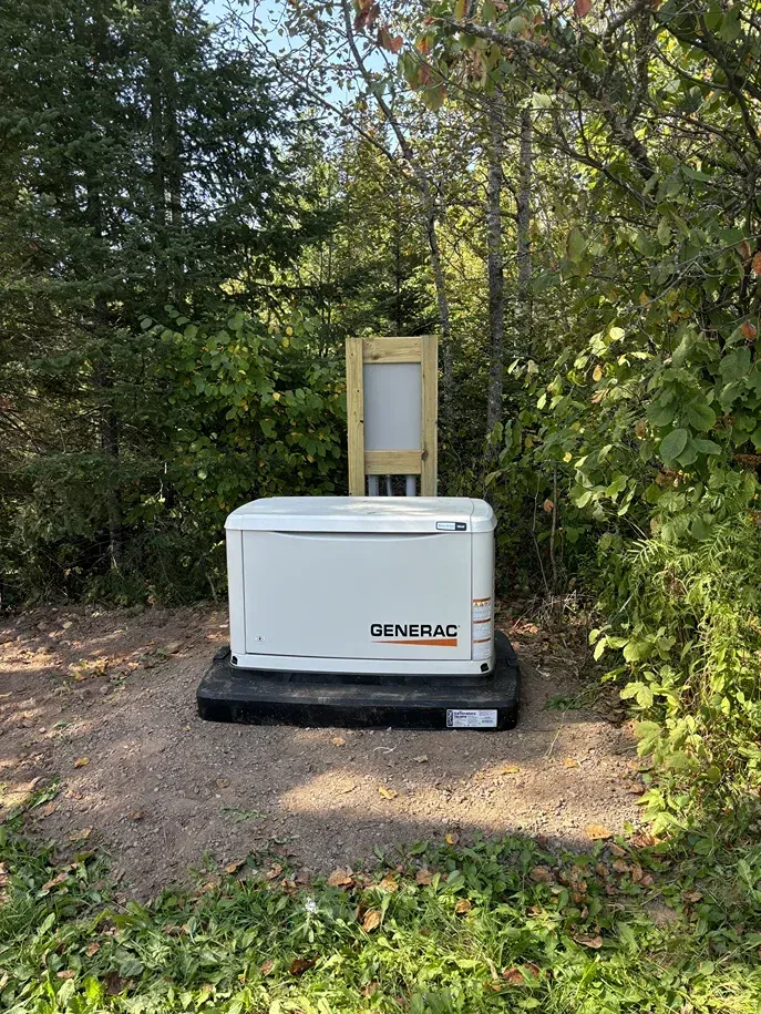A generator is sitting in the middle of a grassy field surrounded by trees.