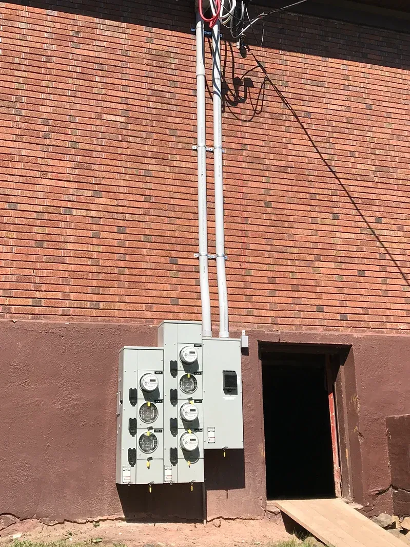 An electrical box is attached to the side of a building.