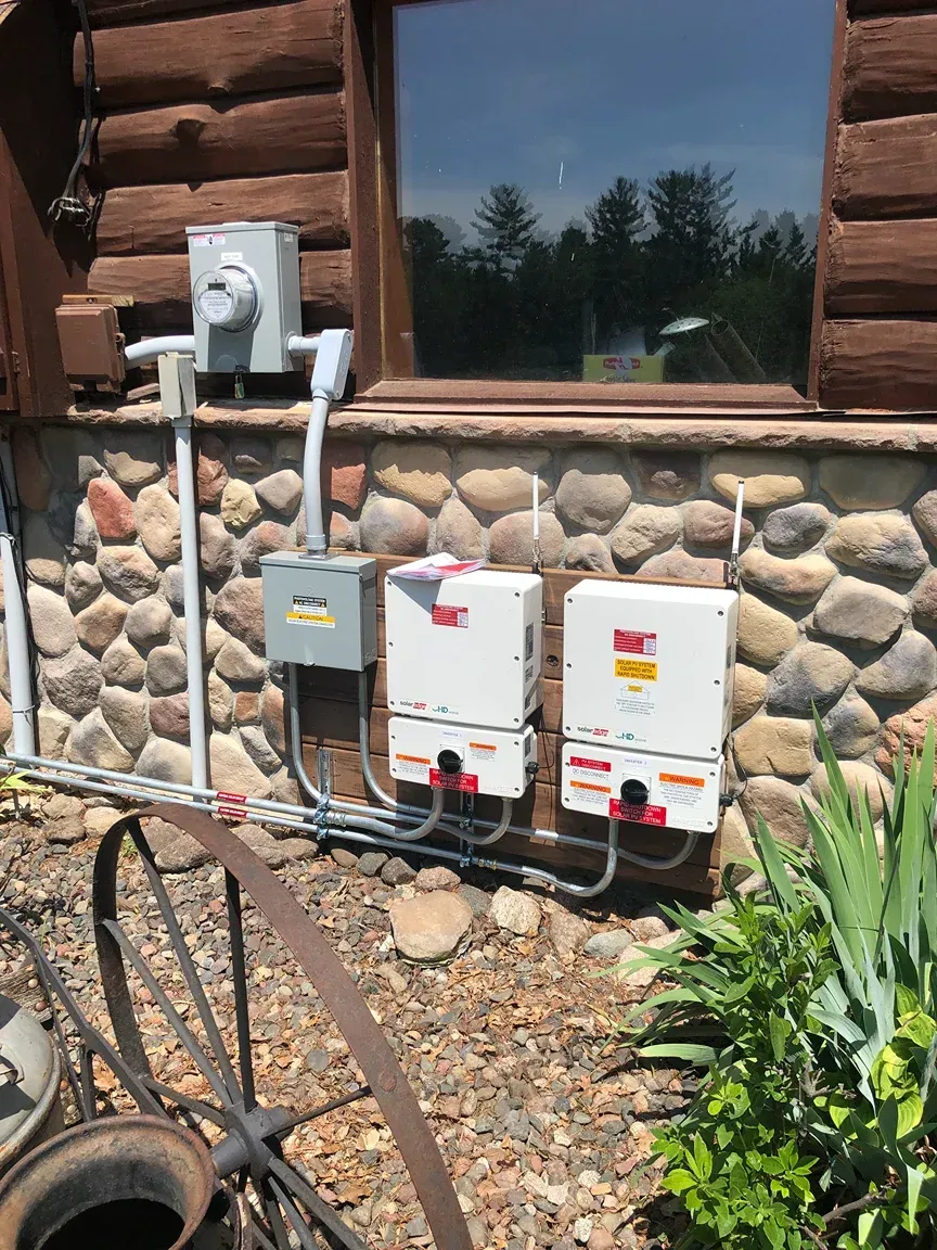 Two solar panels are installed on the side of a log cabin.