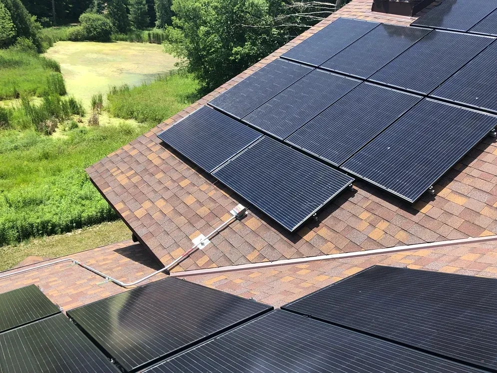 There are many solar panels on the roof of a house.