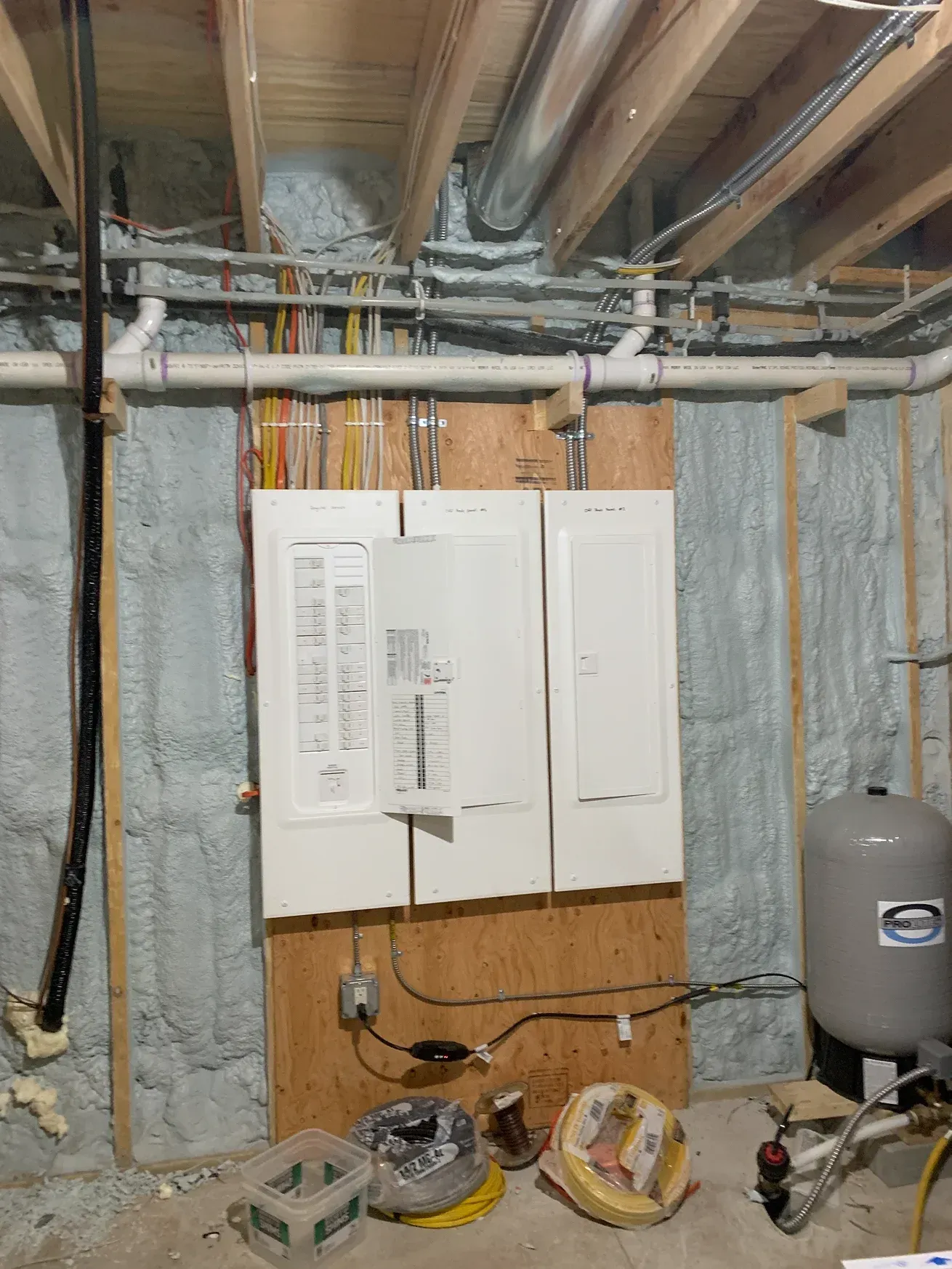 A basement with a lot of pipes and wires on the wall.