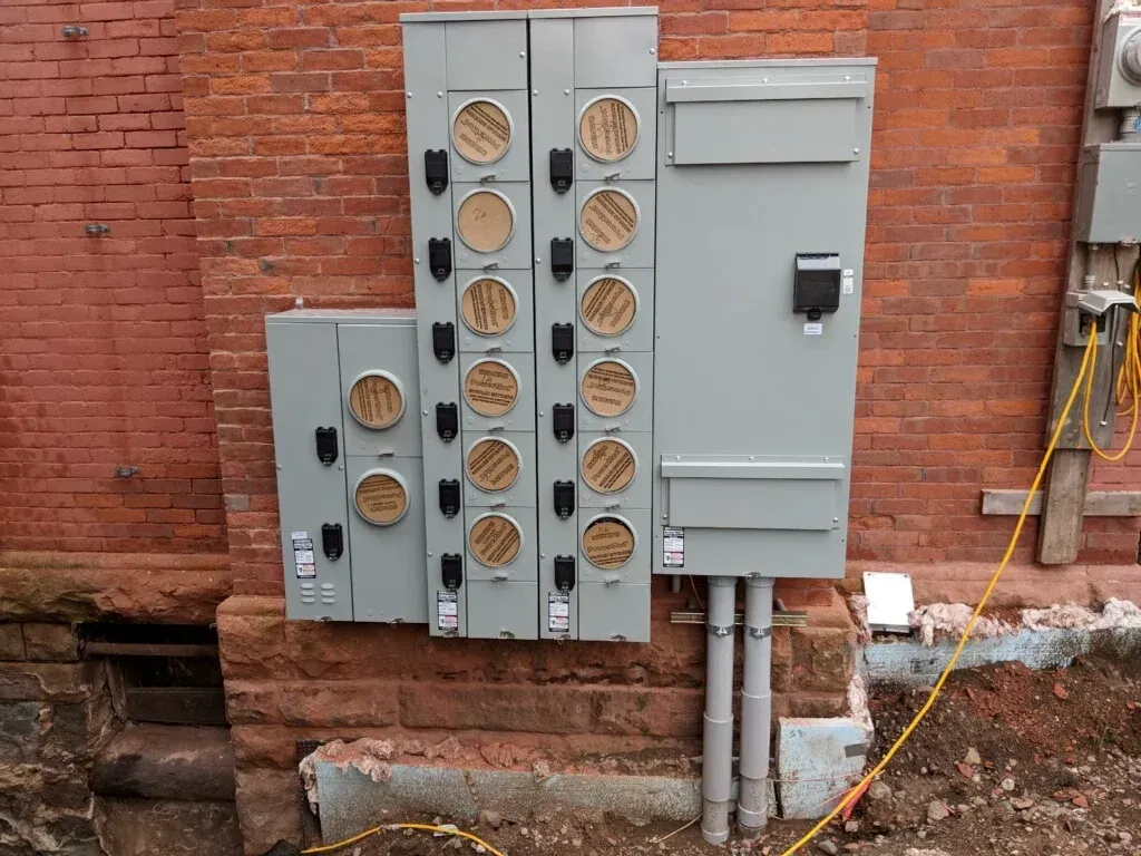 A brick wall with a bunch of electrical boxes on it