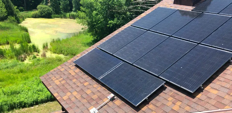 A roof with solar panels on it and a pond in the background.