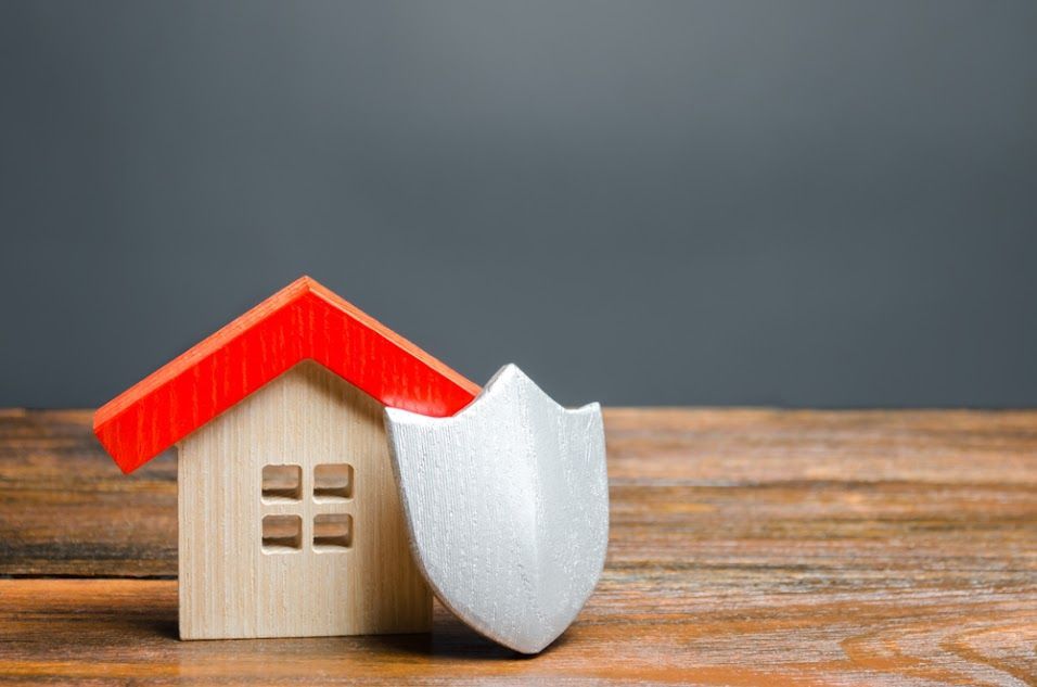A wooden house with a red roof and a shield on a wooden table.