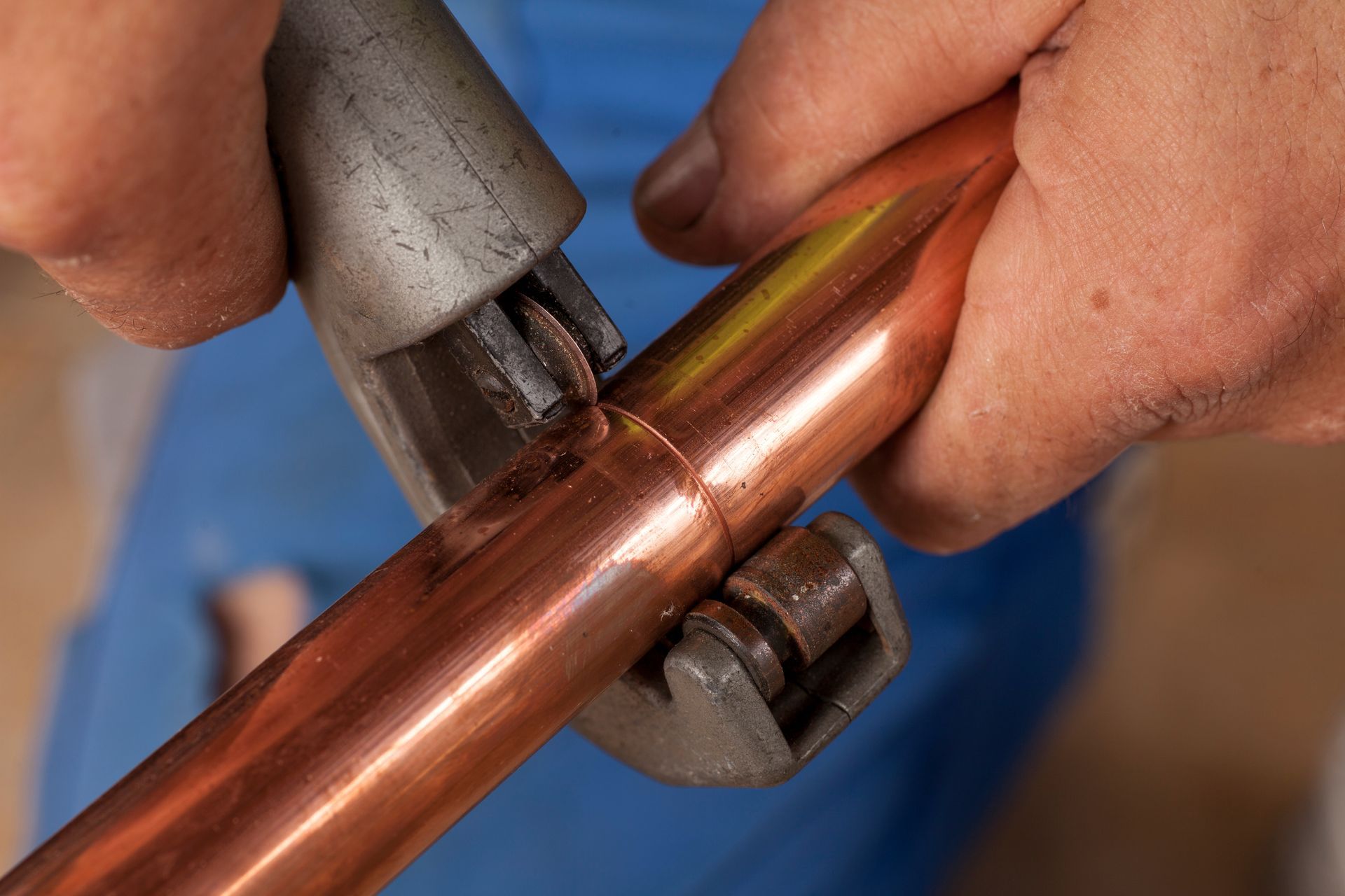 a person is cutting a copper pipe with a pipe cutter
