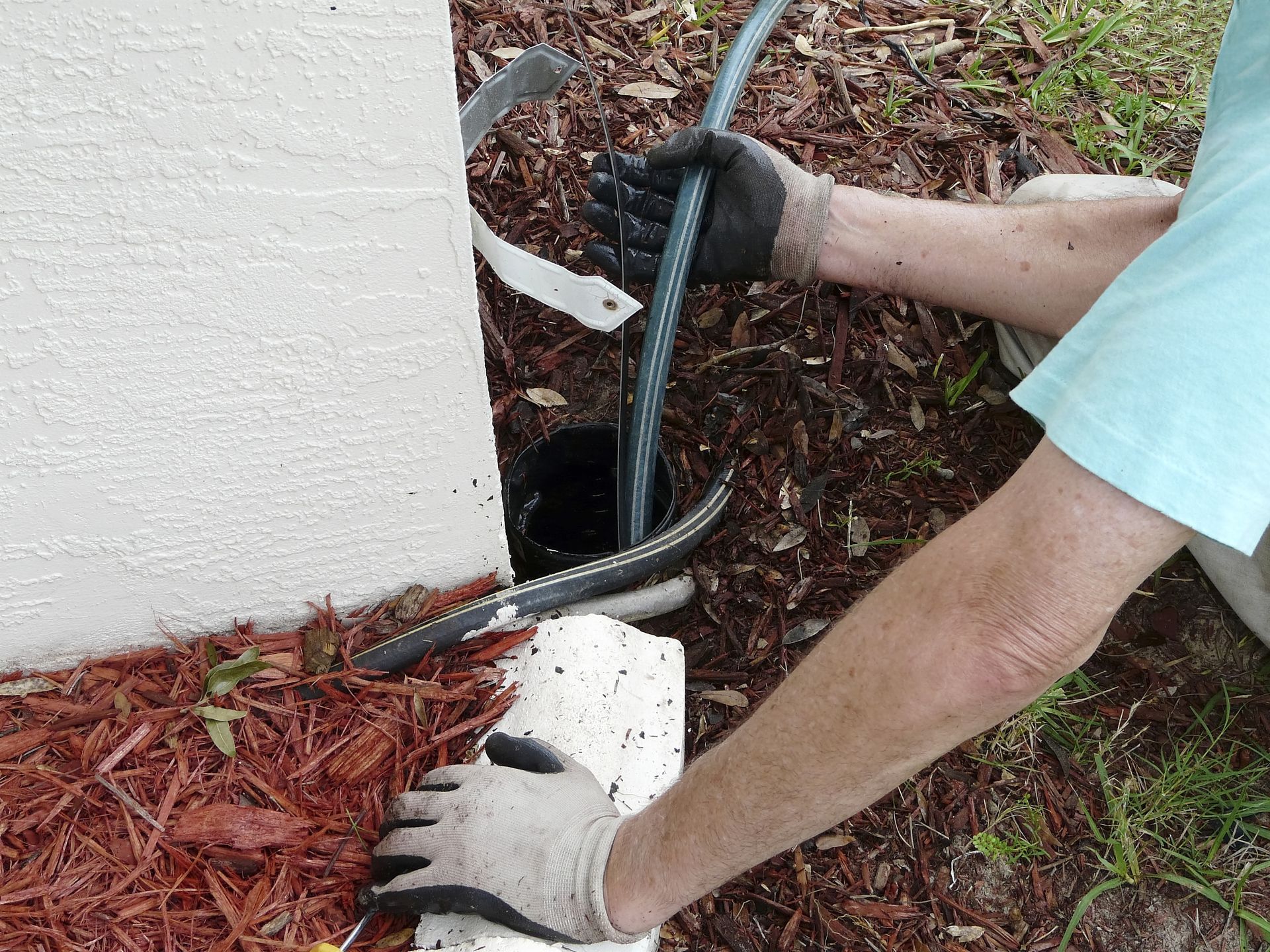 Plumber using a sewer rod to clear a blockage in a drainpipe.