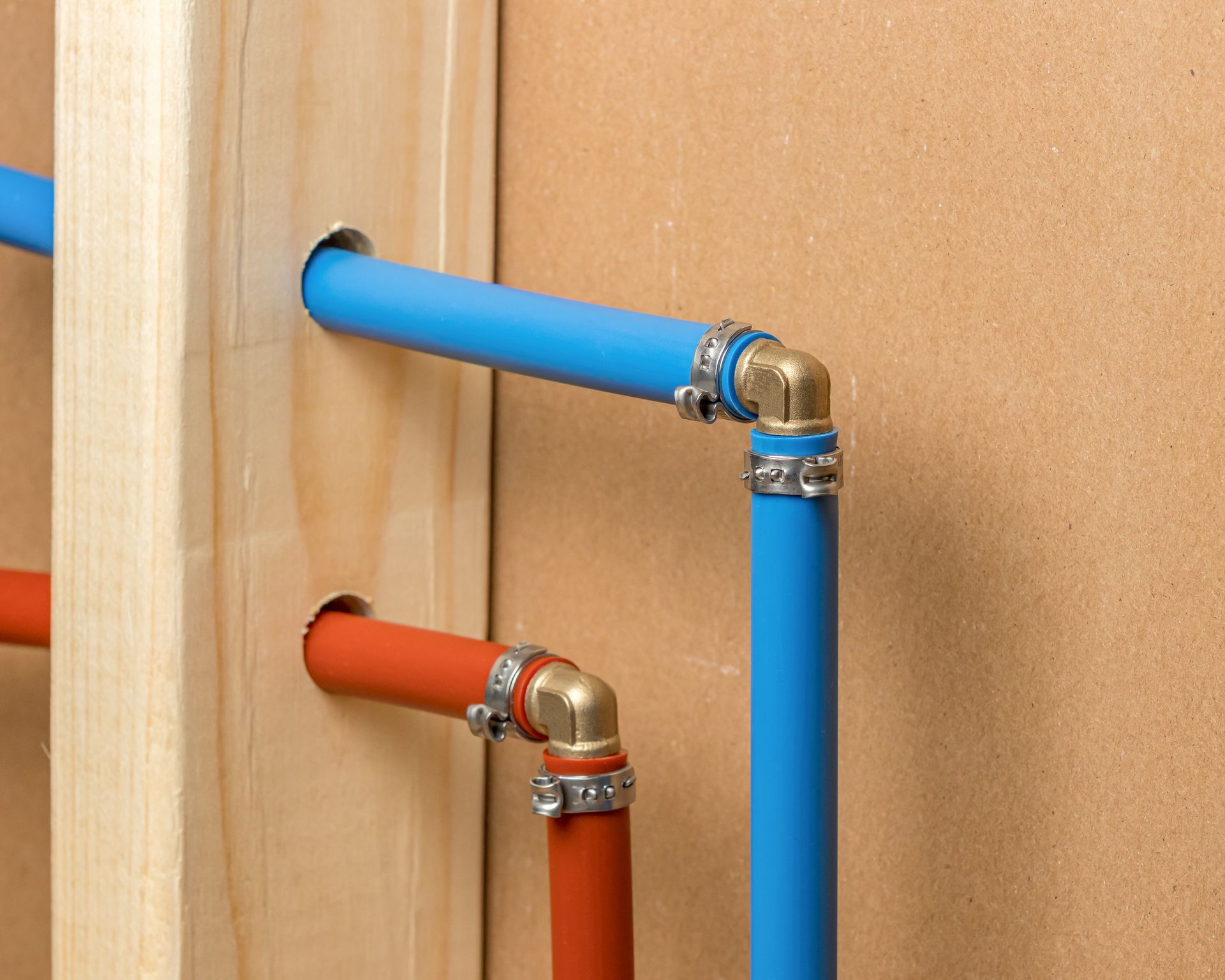 blue and orange pipes are connected to a wooden wall