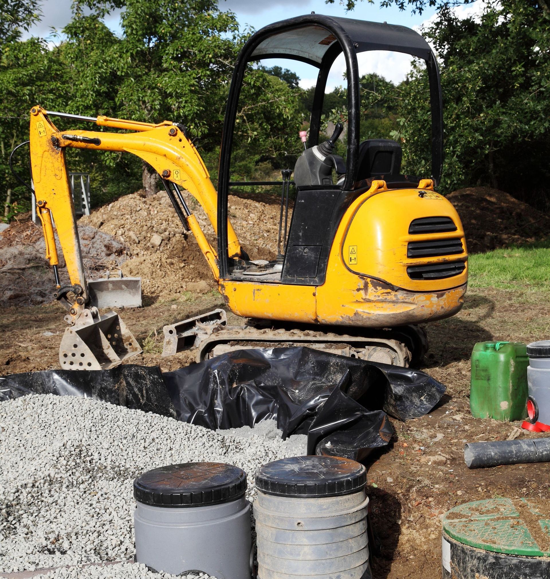 Mini digger installing a sand and gravel filter for sewage.
