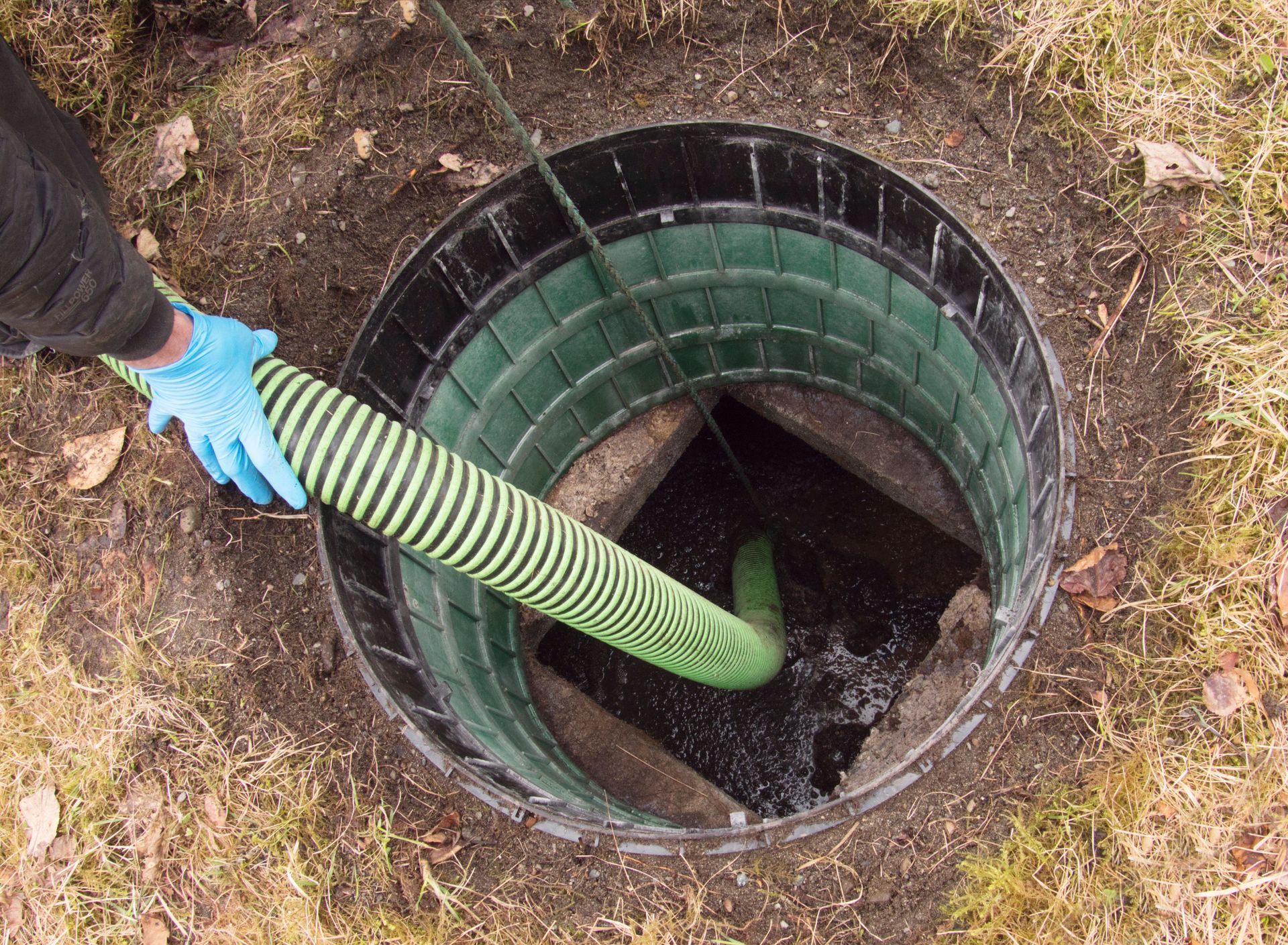 A hose pumping out a home septic tank to remove waste and maintain proper sanitation.