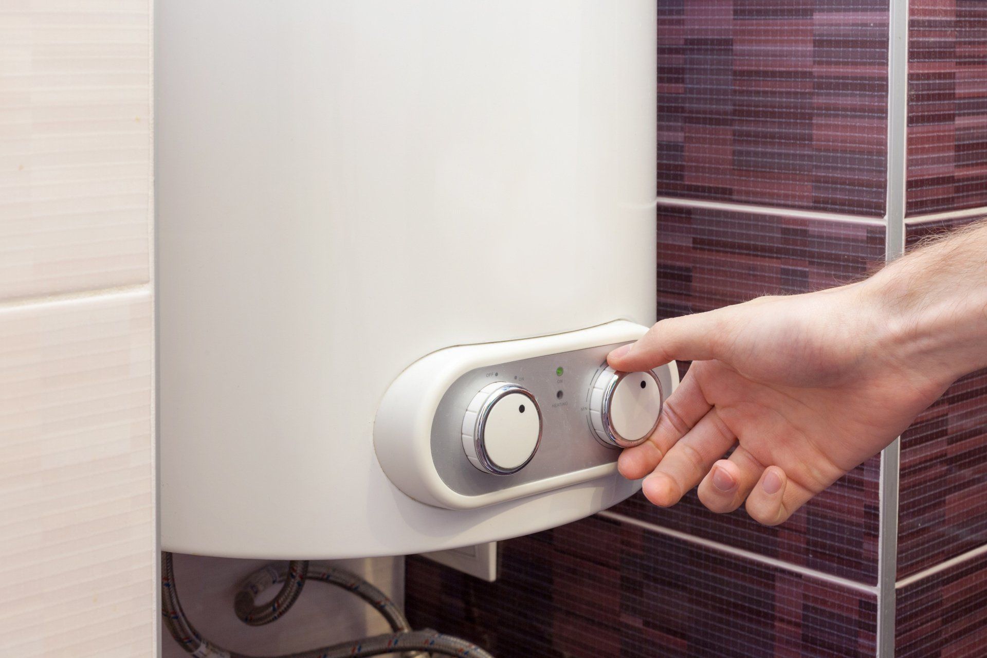 Man's hands adjusting the water temperature on an electric boiler.
