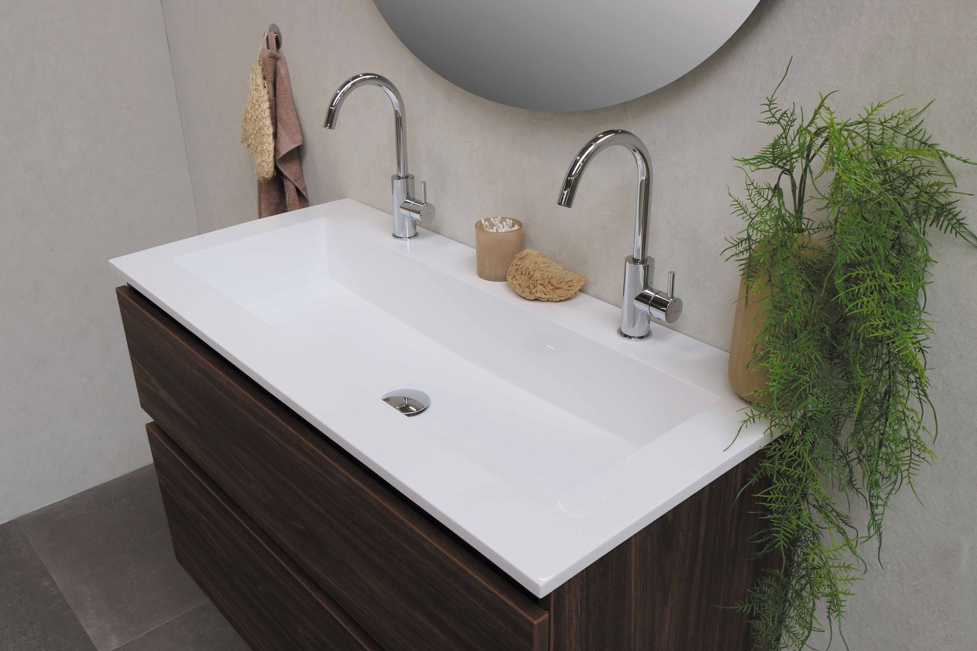 White ceramic sink with two stainless steel faucets installed.