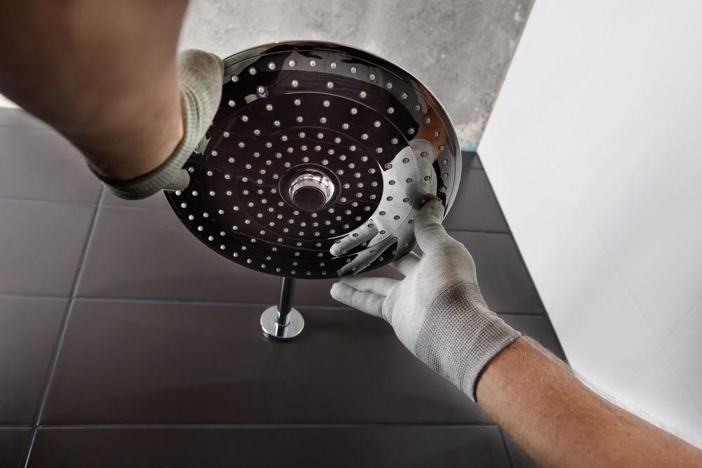 a person wearing gloves is working on a shower head