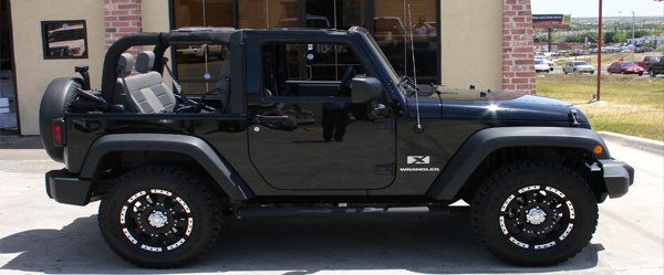 A black jeep is parked in front of a building