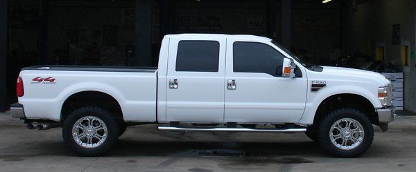 A white pickup truck is parked in front of a garage.