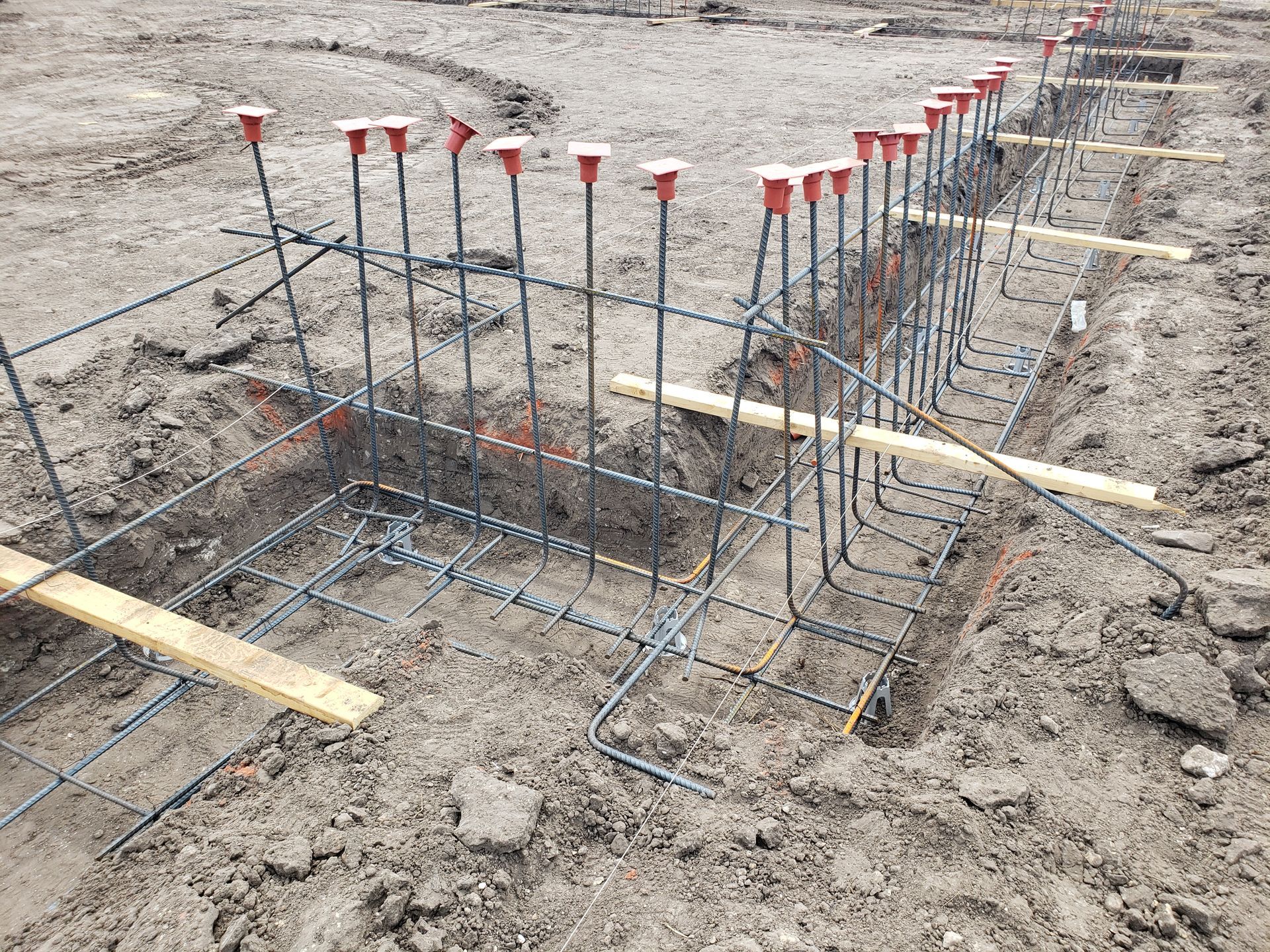 A bunch of metal rods are sitting in the dirt on a construction site.