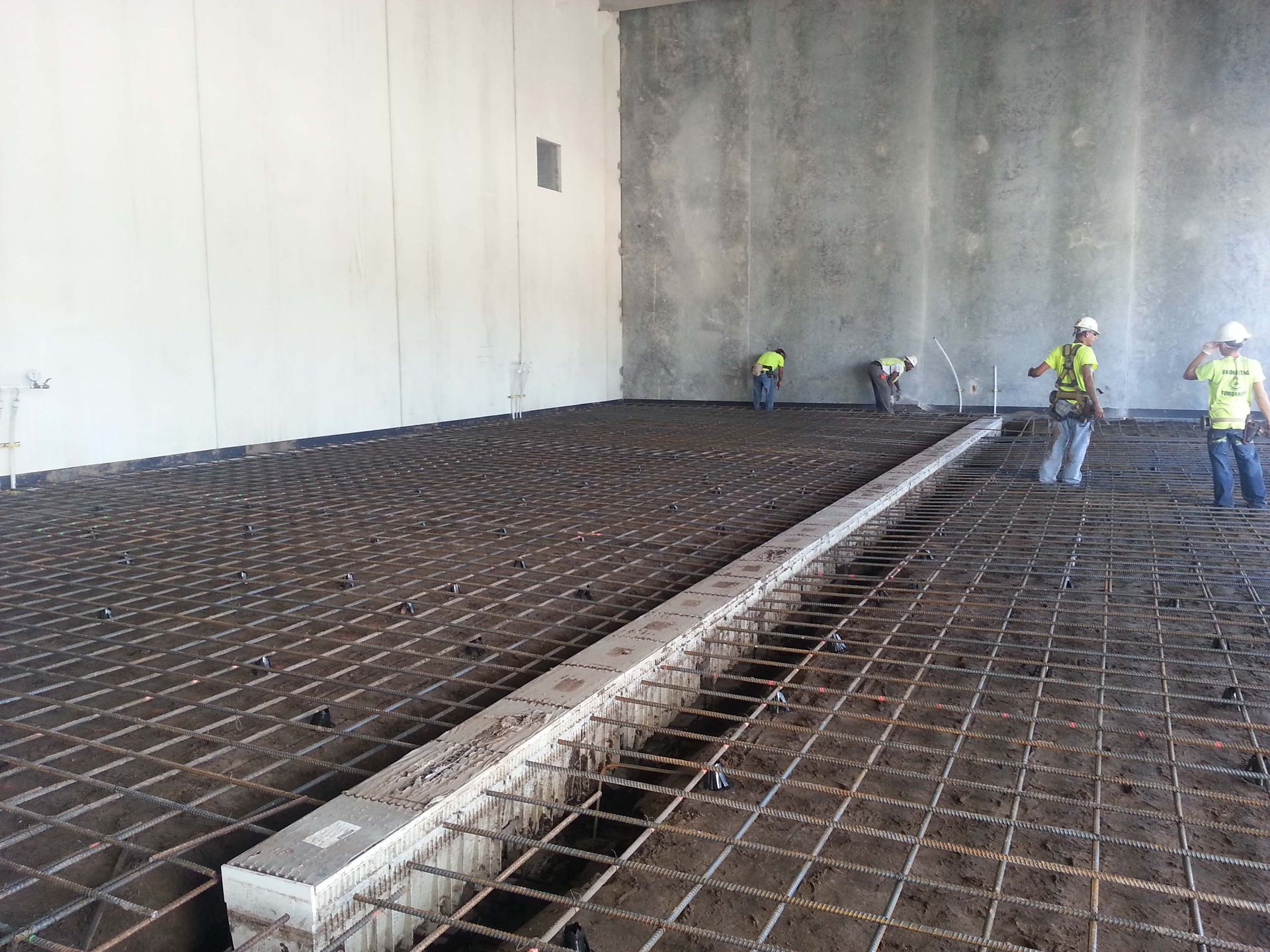 A group of construction workers are working on a concrete floor.