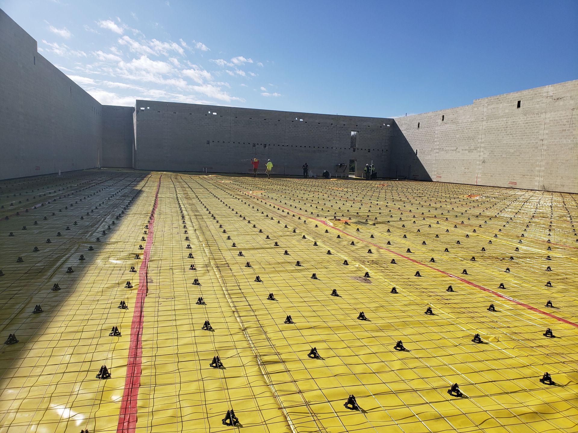 A large building under construction with a yellow tarp on the ground.