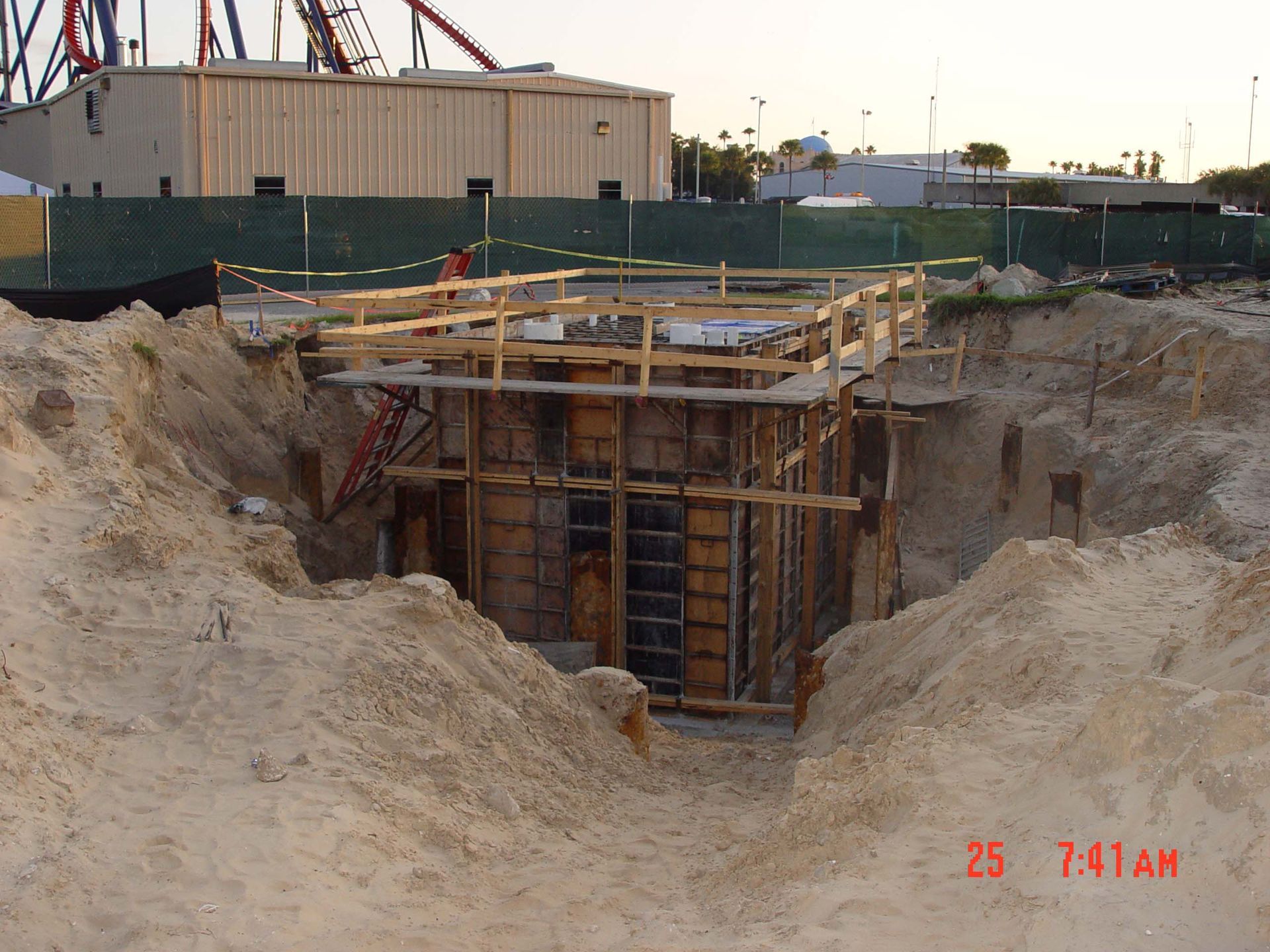 A construction site with a roller coaster in the background